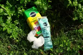 Miracle-Gro plant food and feeder refill packet lie on grass. While not inherently toxic, proper use is key to avoid harming plants.