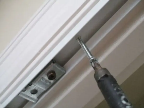 Screwdriver installing a bracket for how to install bifold doors.