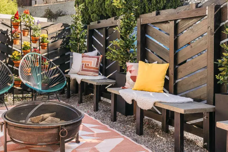 A cozy patio with a diy privacy screen, fire pit, and colorful chairs.